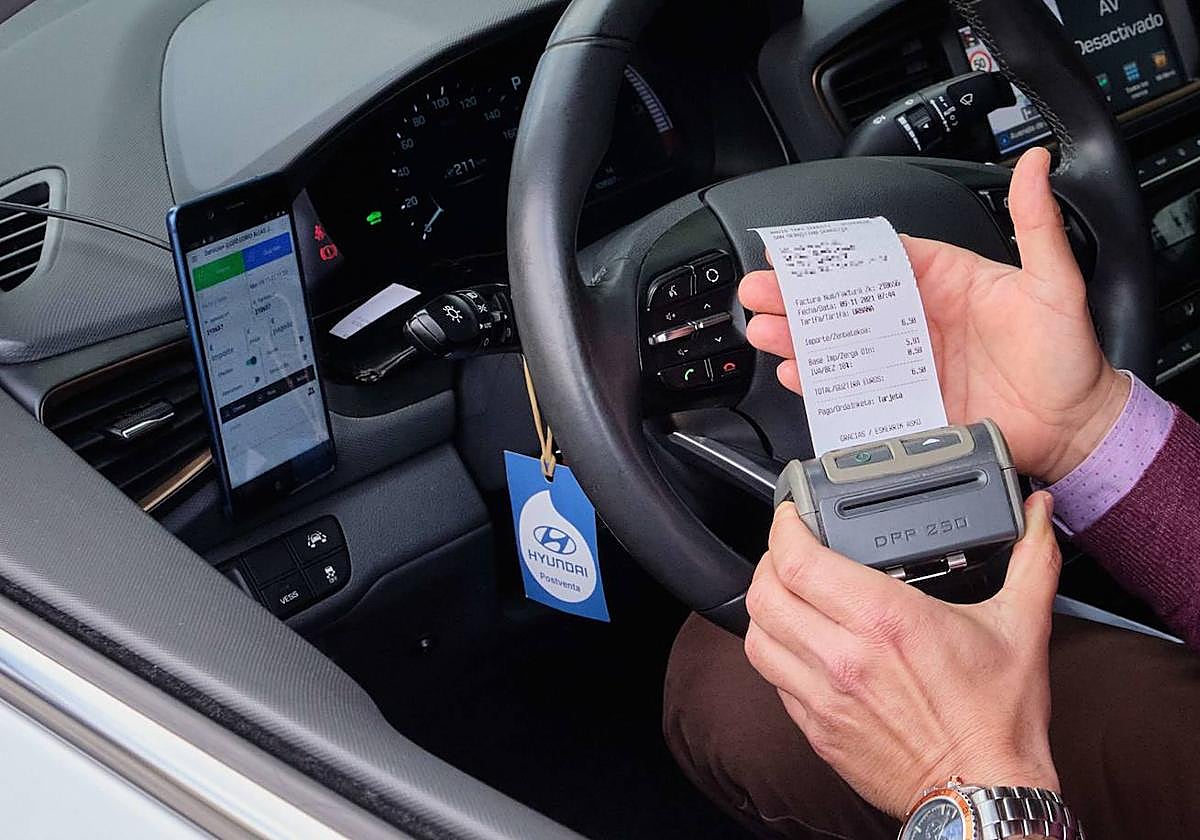 Un taxista donostiarra con un ticket y la aplicación usada por TicketBai.