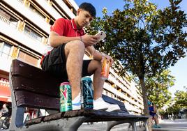 Un joven de Irun consulta su móvil después de haber comprado un par de bebidas energéticas.