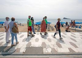 Grupo de jubilados pasea por la playa de Levante de Benidorm.