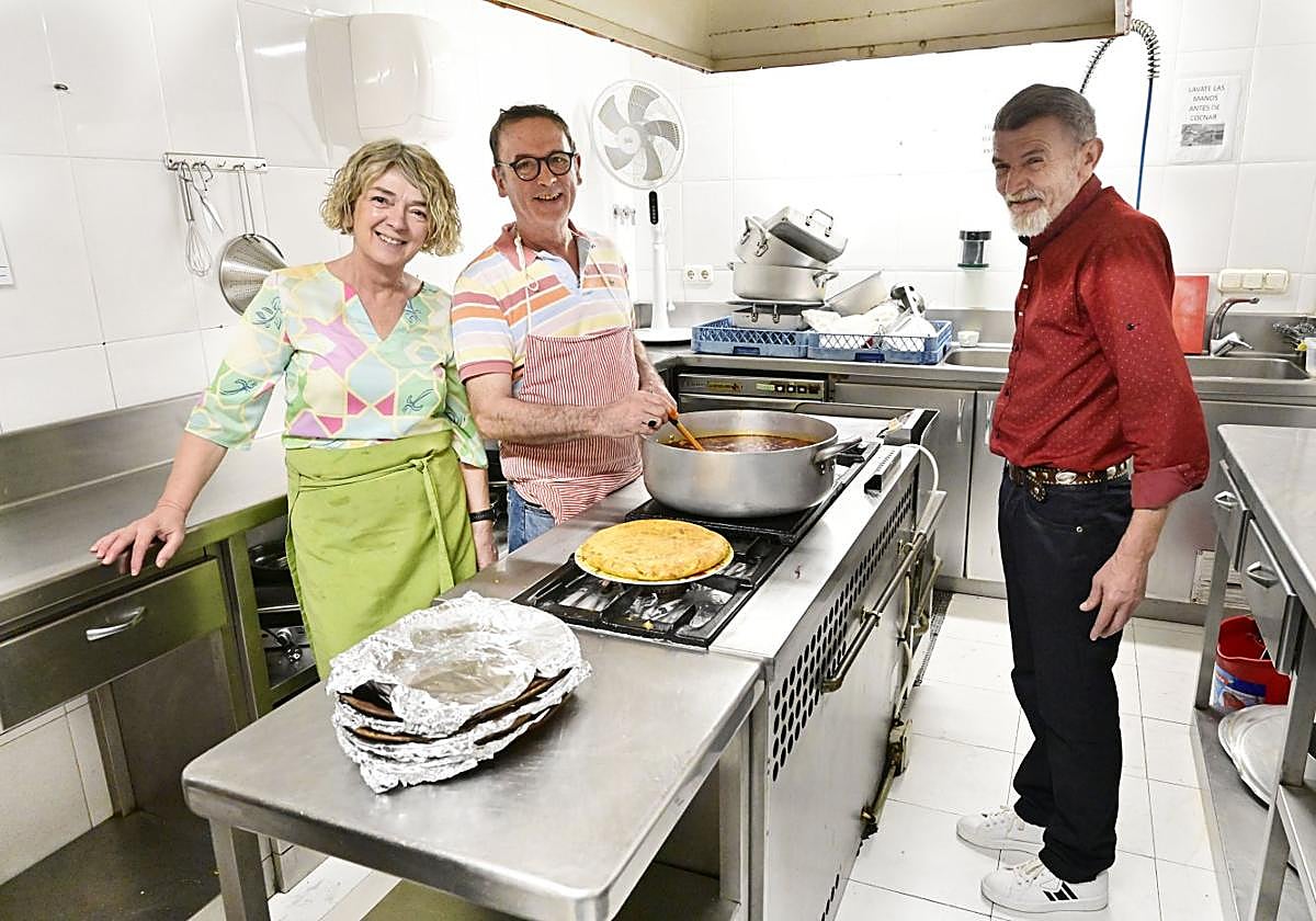 Eloy Ubegun, en el centro, ayudado en la cocina de la residencia por la voluntaria Isabel y el residente Agustín.