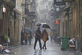 Dos personas pasean este sábado lluvisoso por la Parte Vieja.