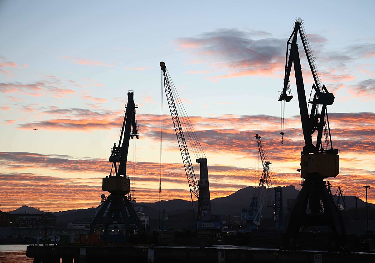 Varias grúas se recortan a contraluz en el cielo del puerto de Pasaia.