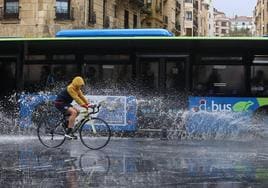 Un autobús levanta una ola de agua a su paso por el Kursaal en Donostia.