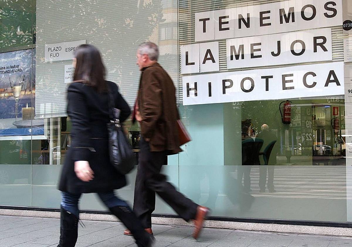 Dos personas caminan junto a una sucursal bancaria.