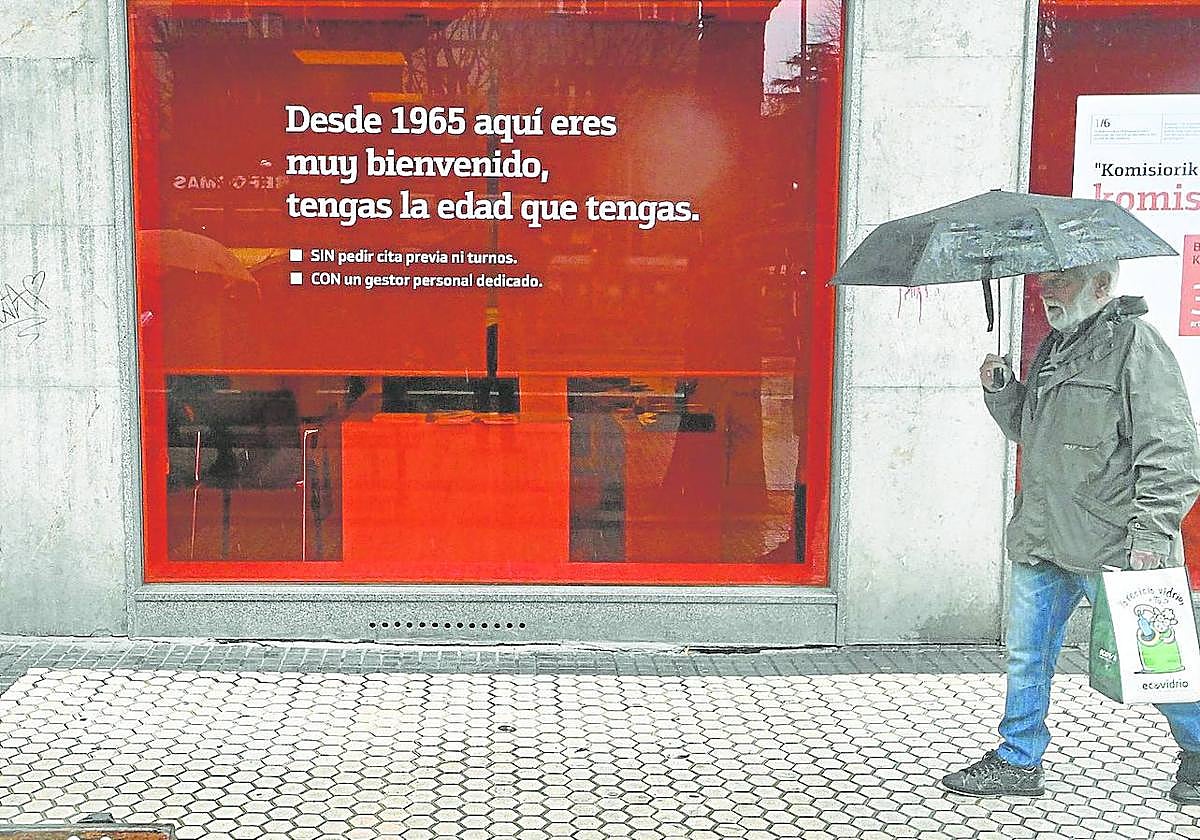 Un hombre pasea delante de una entidad bancaria en San Sebastián.