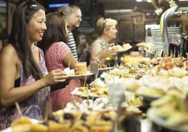 Un grupo de turistas ante una barra de pintxos en la Parte Vieja donostiarra.