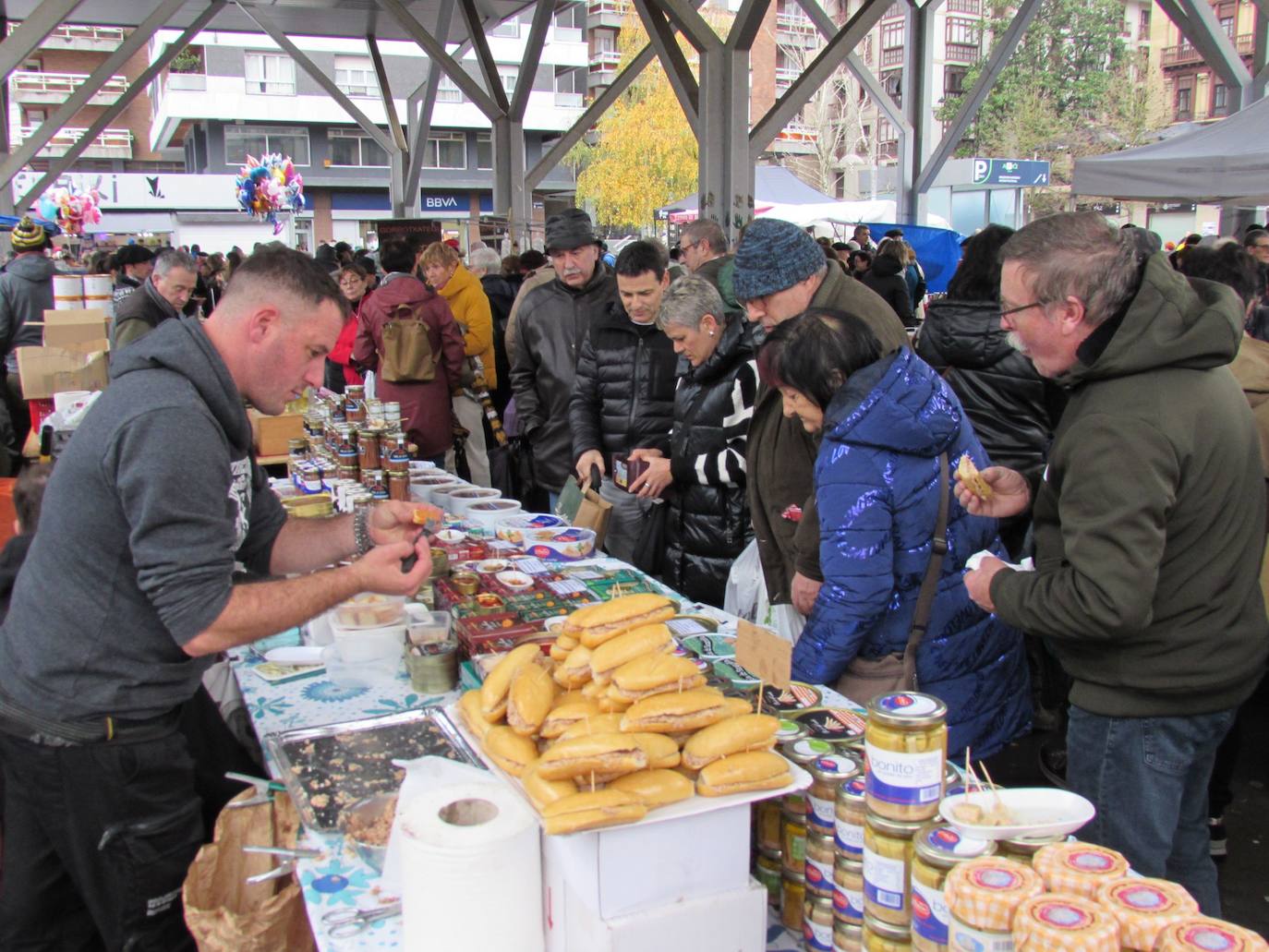 Imagen secundaria 1 - Arriba, una cuadrilla tomando un trago de sidra en la calle. Muchos consumidores realizaron sus compras navideñas en los puestos de alimentación instalados en la plaza Biteri. Debajo, niños comiendo talo con txistorra