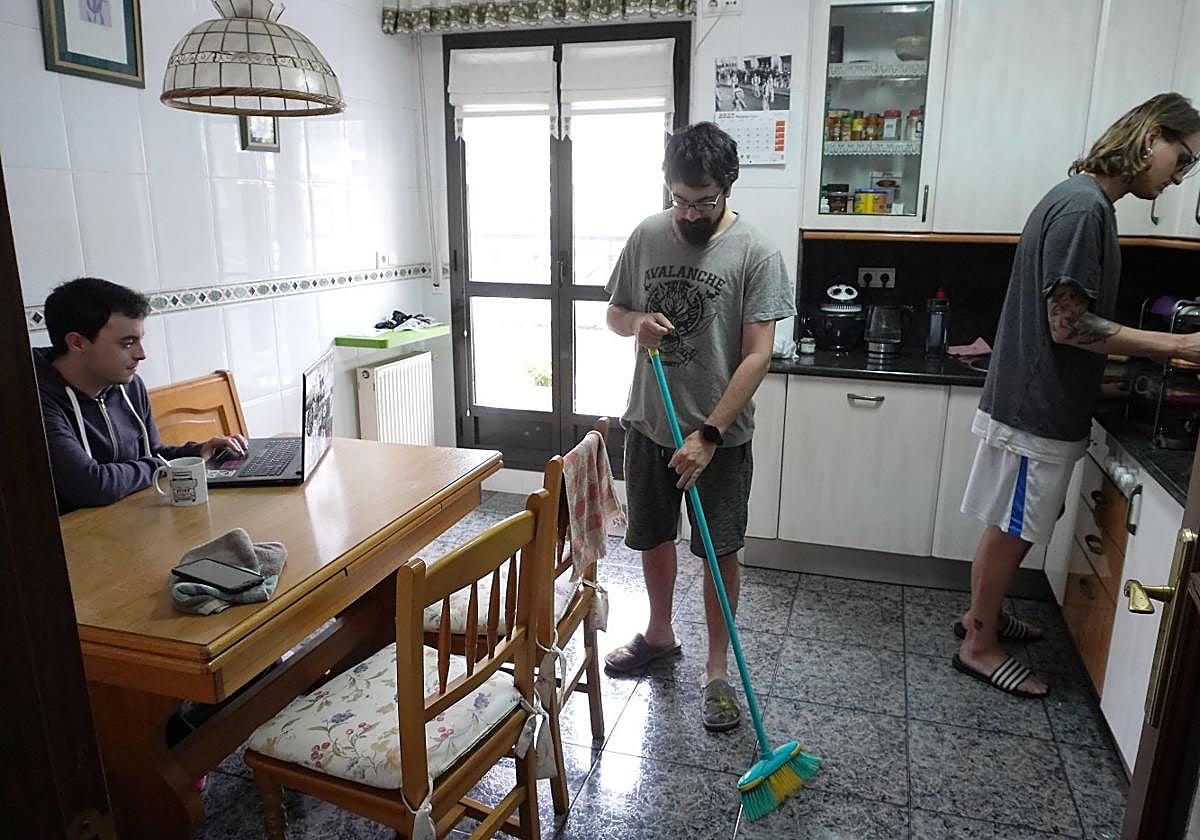Jóvenes que comparten un piso de alquiler en Lasarte-Oria realizan diversas tareas en la cocina.