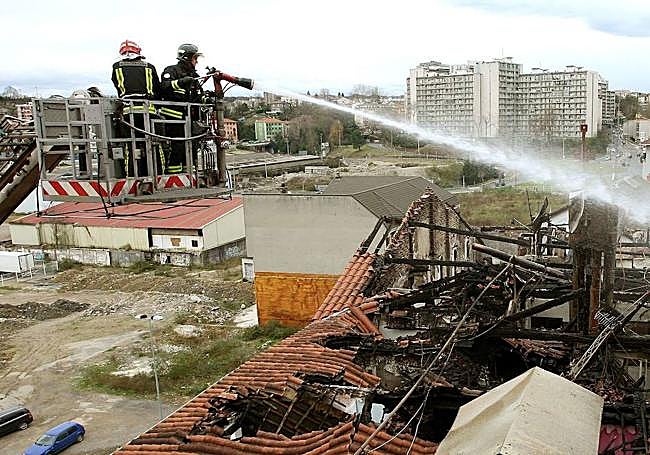 Dos bomberos tratan de apagar los rescoldos del fuego que hizo desaparecer una planta.