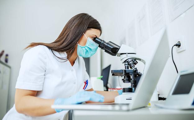 Una investigadora mira por el microscopio en el laboratorio.