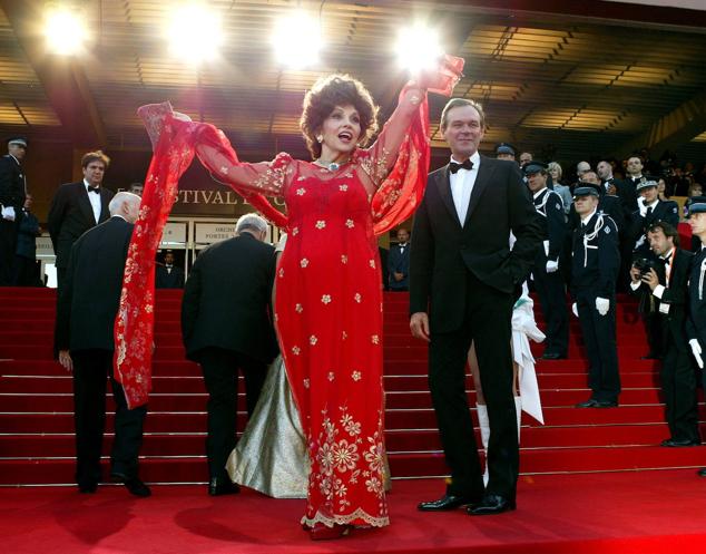 La actriz italiana Gina Lollobrigida, junto al entonces ministro de Cultura francés Jean-Jacques Aillagon, saluda a la multitud durante la alfombra roja de la apertura del 56º Festival Internacional de Cine de Cannes.