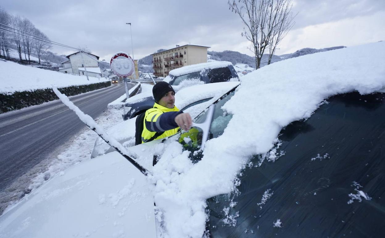 Un hombre quita la nieve de su vehículo.