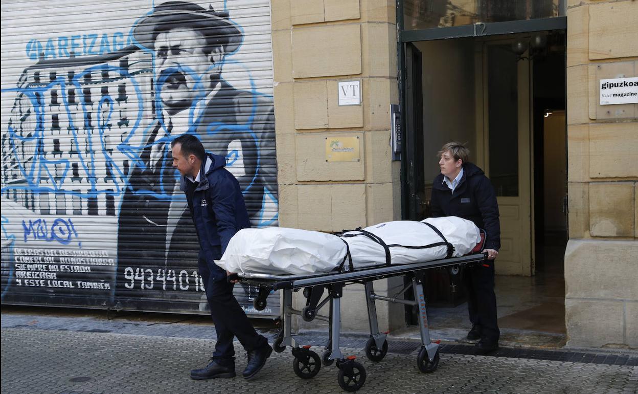 Personal de funeraria traslada el cuerpo del fallecido.