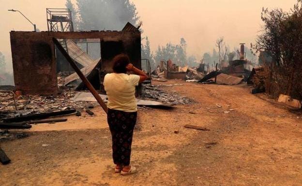 A woman observes a house destroyed during a fire in the town of Santa Juana