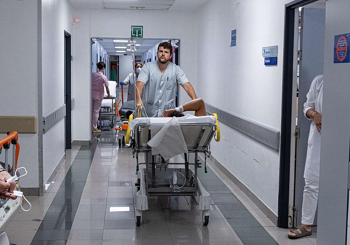 Un celador traslada a a un paciente en camilla dentro de las Urgencias del Hospital Universitario Donostia.