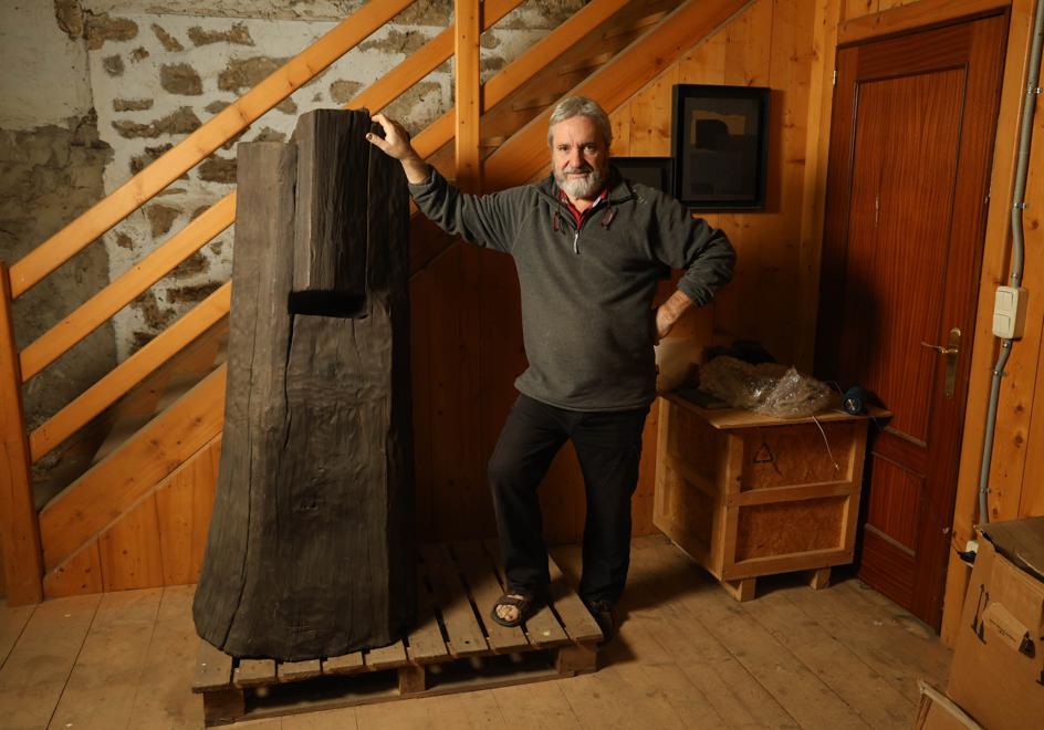 Koldobika Jauregi posa en su caserío de Alkiza con 'Altxatzeko harriak', la obra de madera que llevó a Alemania en su 'dúo artístico' con Chillida en el 2000.