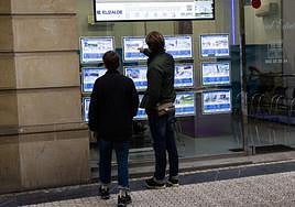 Una pareja consulta el escaparate de una inmobiliaria en el centro de Donostia.