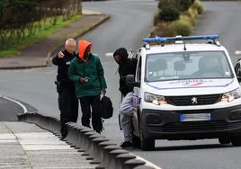 Un policía galo señala el camino de regreso a Irun a dos migrantes tras ser interceptados en un punto de Hendaya.
