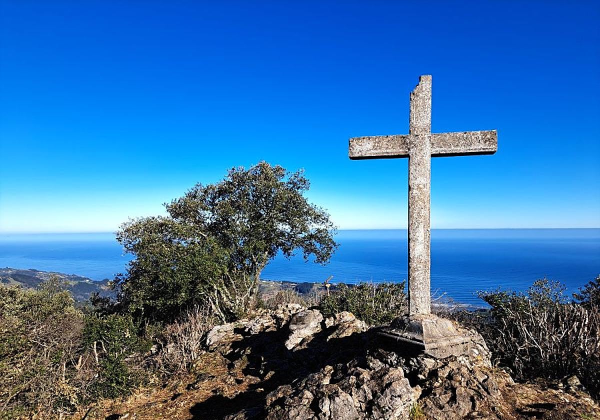 La gran encina se erige como protagonista junto a la cruz de Arno y su buzón ante un precioso Cantábrico.