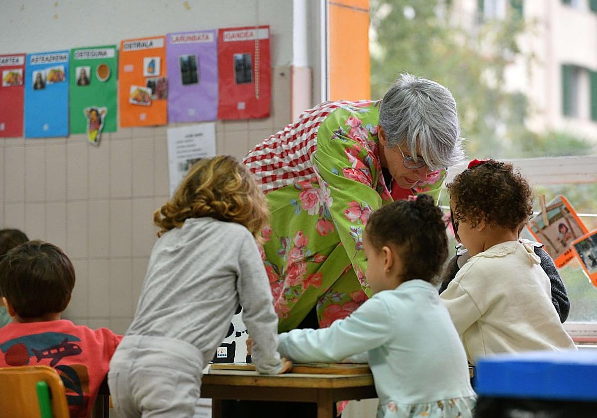 Una profesora atiende a tres alumnas en un aula.