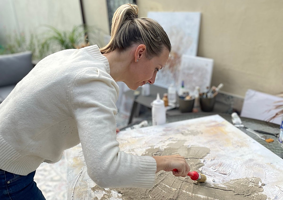 Imagen secundaria 1 - Una pintura con matices metalizados, Mireia Izquierdo en el proceso de creación y otra pintura con tonalidades neutras 