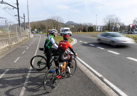 Ciclistas esperan a incorporarse a la carretera, con la rotonda al fondo de la imagen.