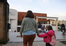 Una madre lleva a su hija al colegio.