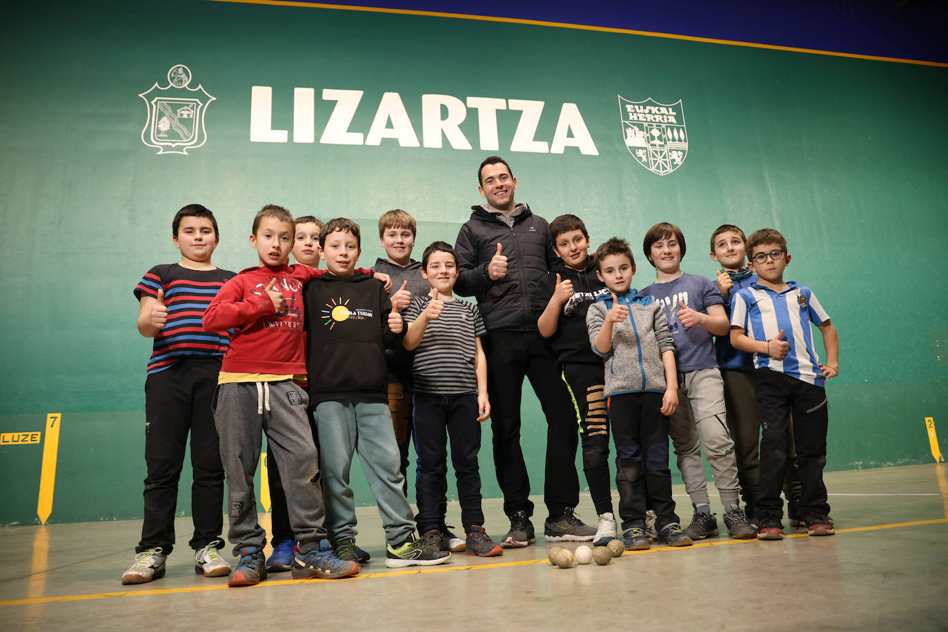 Erik Jaka, rodeado de varios pelotaris a los que entrena en su pueblo, en Lizartza.