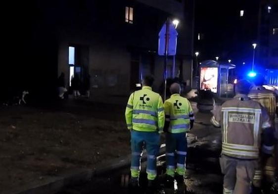 Personal sanitario y bomberos ante el edificio incendiado.