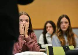 Una joven se tapa la cara con las manos en un aula.