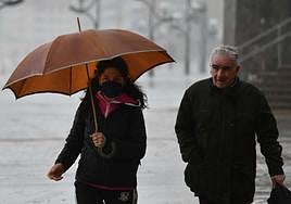 Dos personas pasean en Zarautz bajo la lluvia.