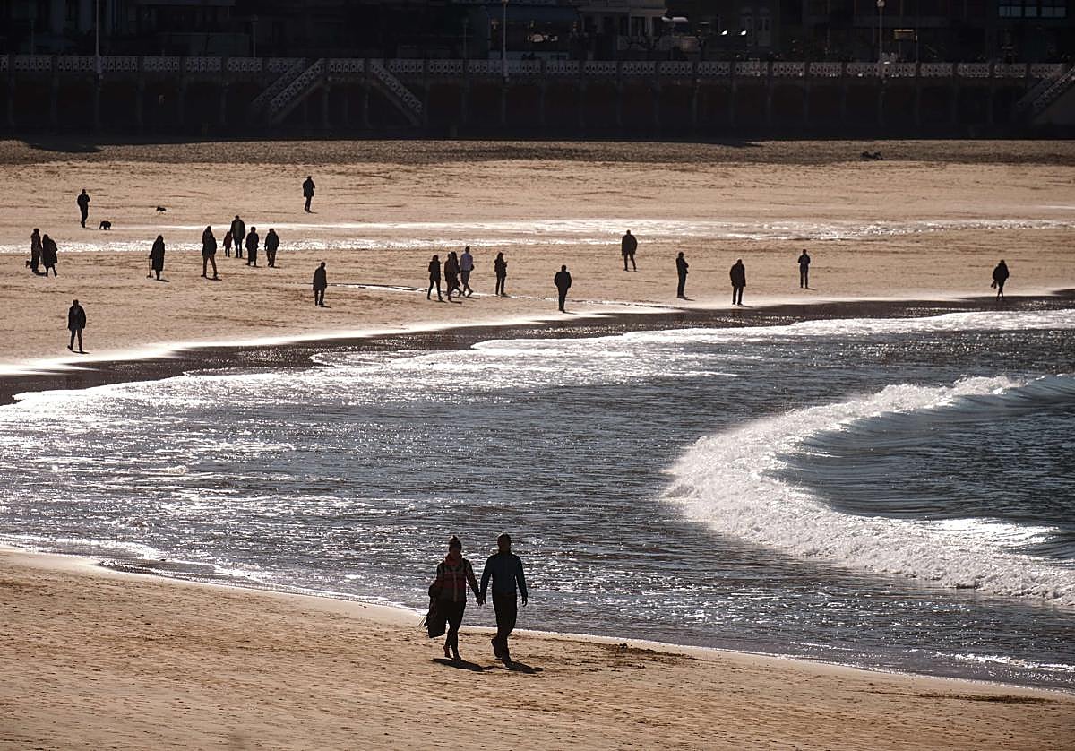 Una pareja camina de la mano por la orilla de la playa de La Concha