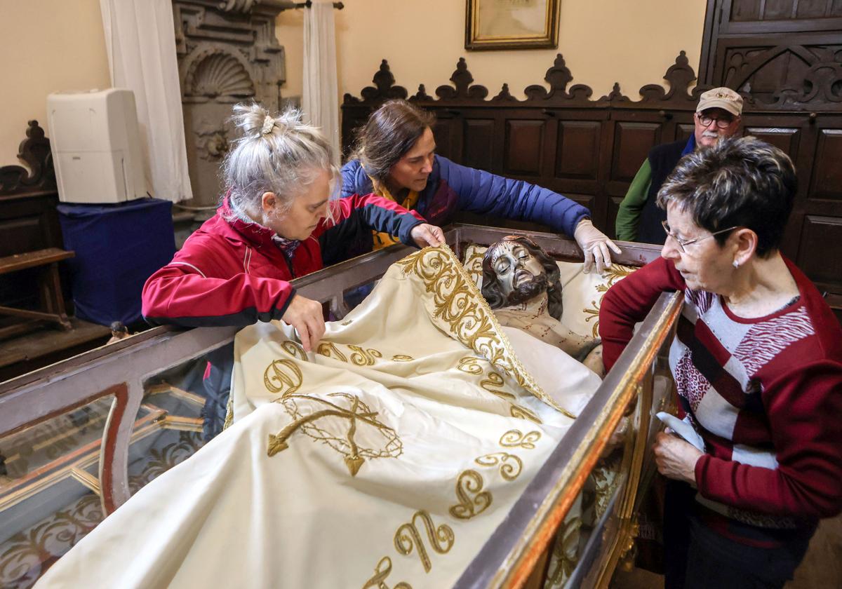 Cuatro voluntarios colocan el sudario de Cristo en un paso que saldrá en la procesión de Viernes Santo en Segura.