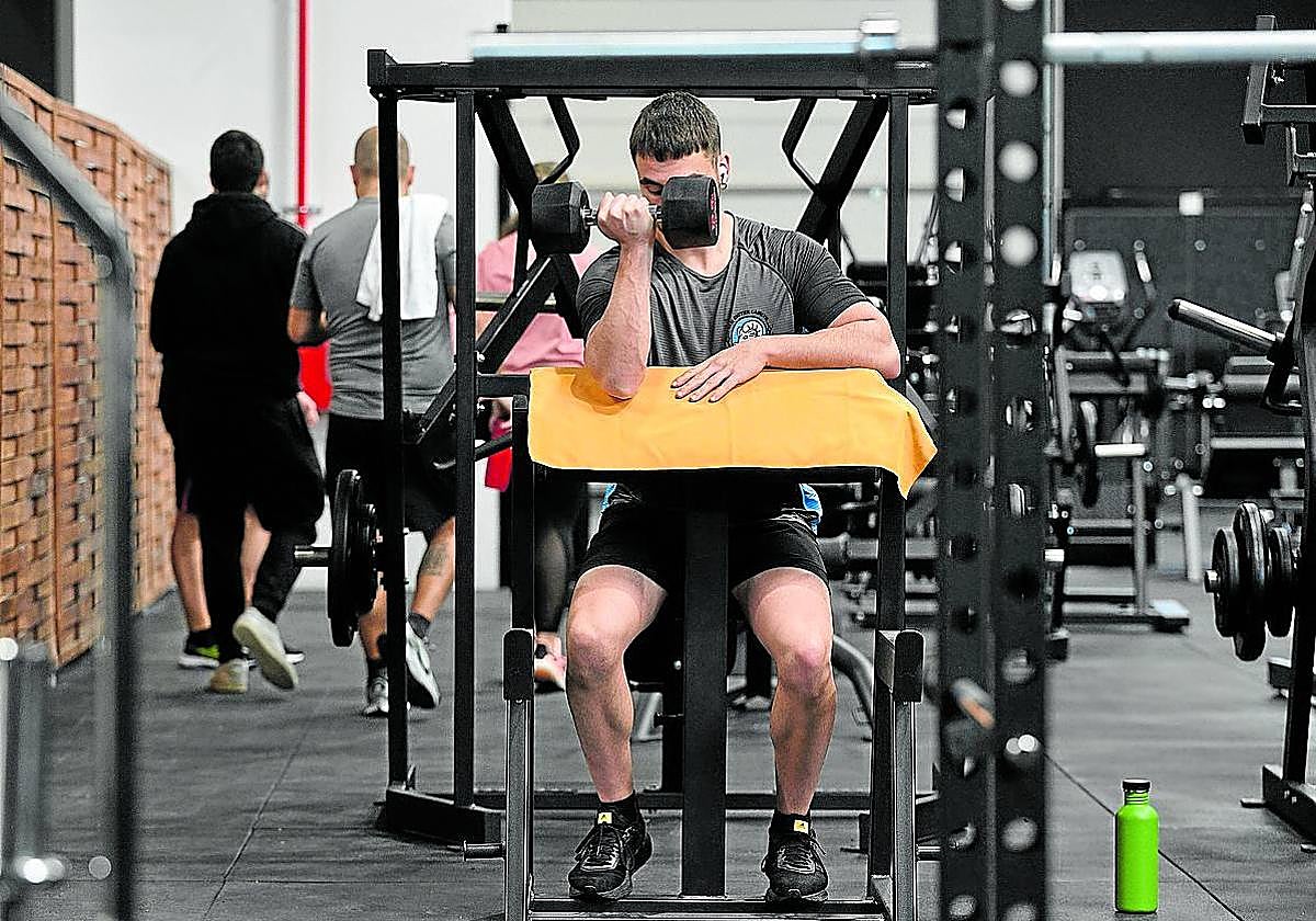 Un joven levanta una mancuerna en un gimnasio.