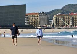 Dos personas paseando por la playa de la Zurriola de Donostia, disfrutando del buen tiempo.