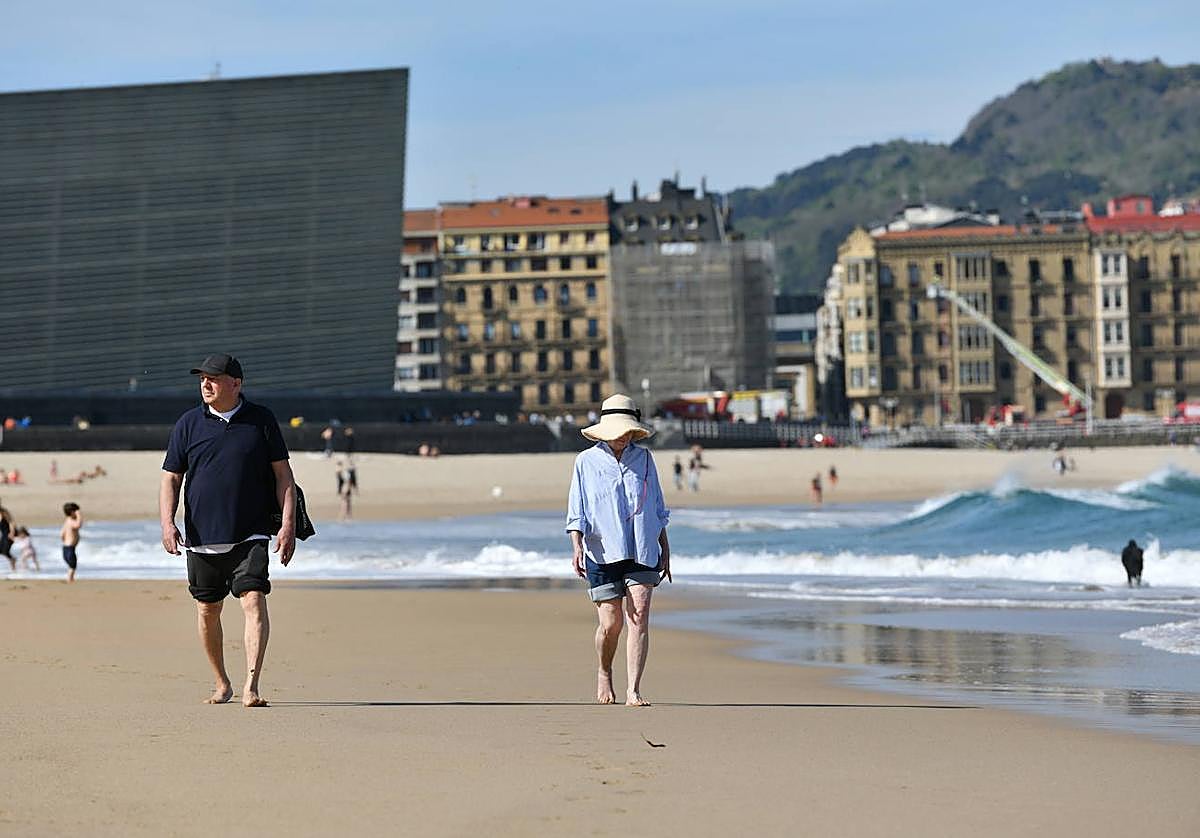 Dos personas paseando por la playa de la Zurriola de Donostia, disfrutando del buen tiempo.