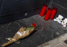 Una rosa y varias velas y peluches depositadas en recuerdo de la mujer y sus dos hijos a la entrada de la vivienda donde fueron asesinados el martes por su marido y padre en Prat de Llobregat. La madre nunca denunció una agresión.