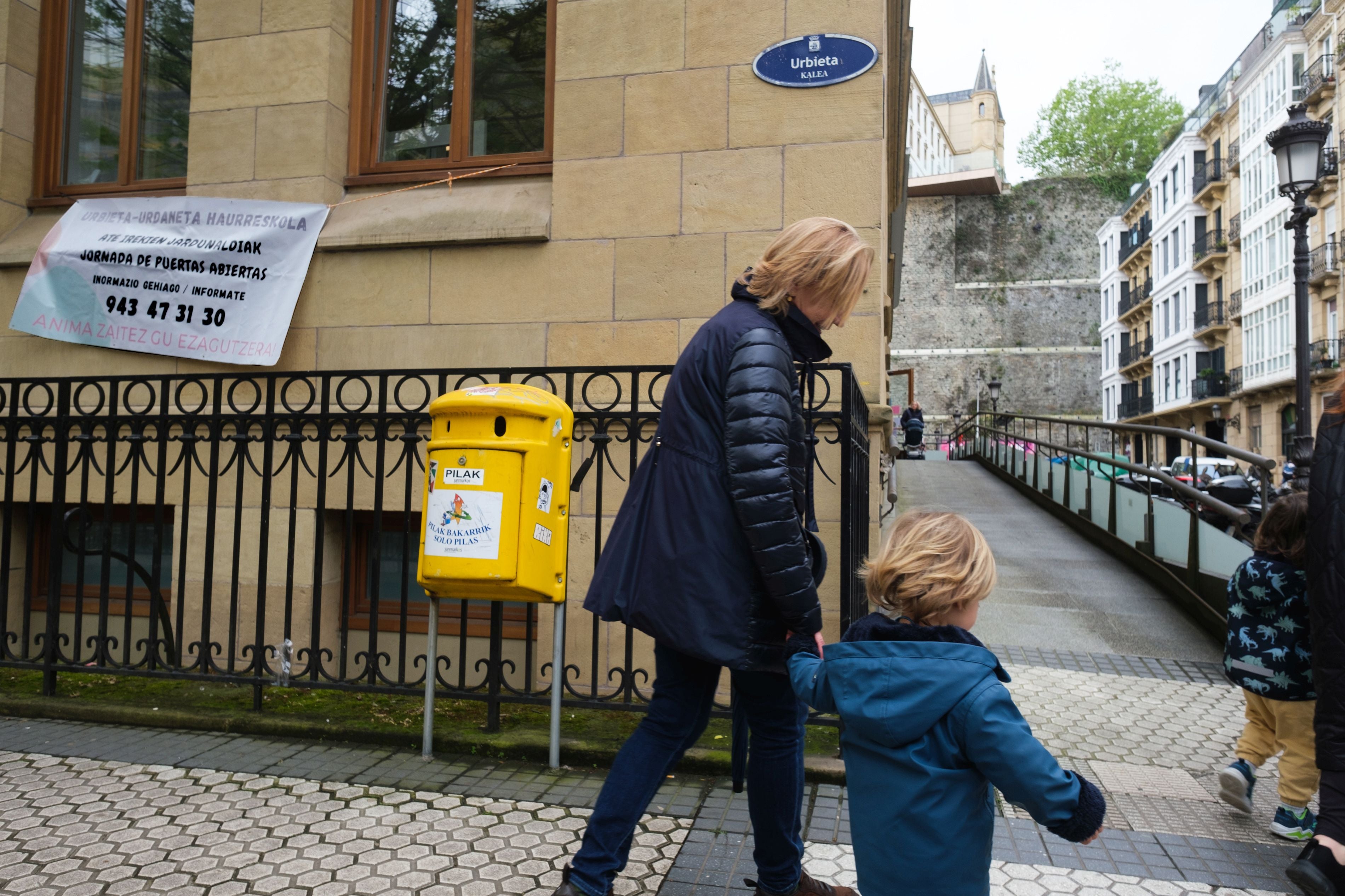 Una mujer se acerca con un niño de la mano a la entrada de la haurreskola de Urbieta Urdaneta, en Donostia.