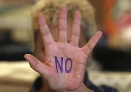 Una mujer muestra un 'No' pintado en la palma de su mano.