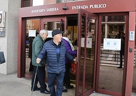 Personas mayores observan los carteles informativos que tiene la Hacienda guipuzcoana en su sede de Errotaburu.