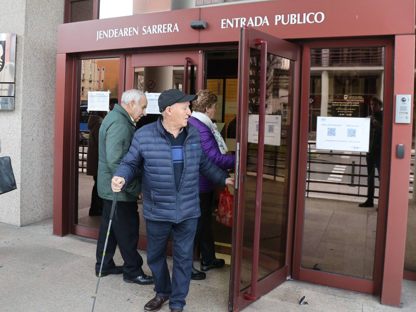 Personas mayores observan los carteles informativos que tiene la Hacienda guipuzcoana en su sede de Errotaburu.