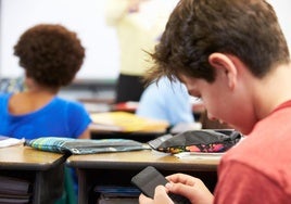 Un adolescente utiliza el móvil durante una clase.
