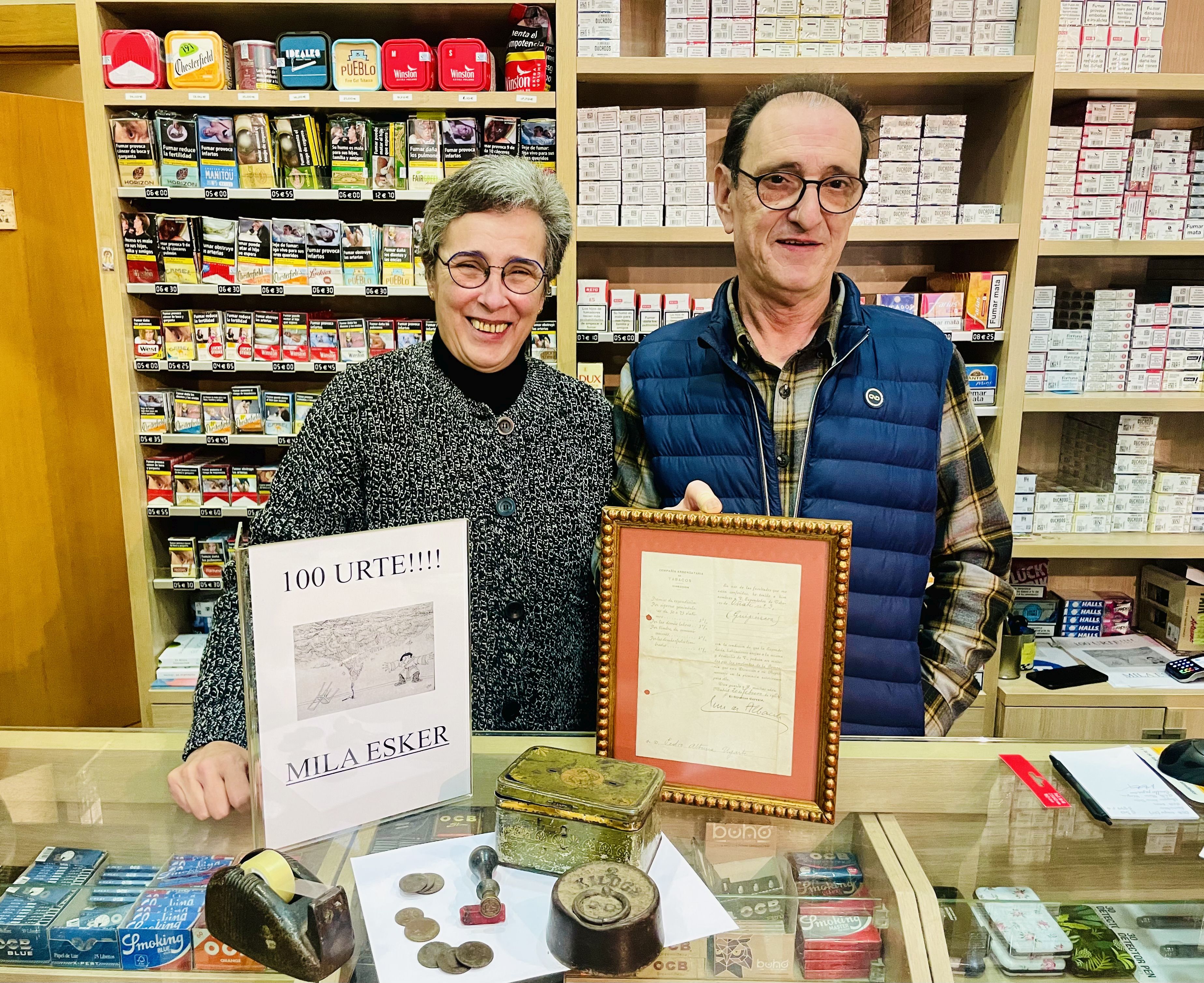 Ixiar Unamuno y Miel Anduaga en el mostrador con los cuadros conmemorativos y artículos antiguos.