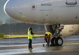 Dos operarios revisan un avión de Iberia en la pista del aeropuerto de Hondarribia.