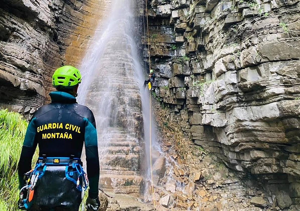 Un agente de la Guardia Civil de montaña observa el descenso de un compañero en el lugar del siniestro.