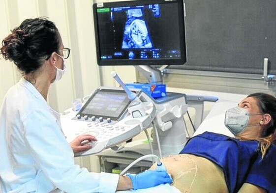 Una médico realiza una ecografía a una mujer embarazada.