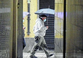 Un hombre camina por la calle con una mascarilla.