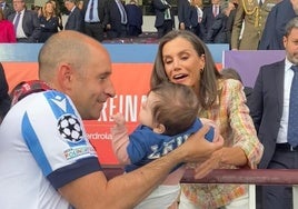 La reina Letizia cogiendo a la pequeña aficionada en brazos.