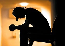 Un joven sentado en un banco con gesto meditativo.