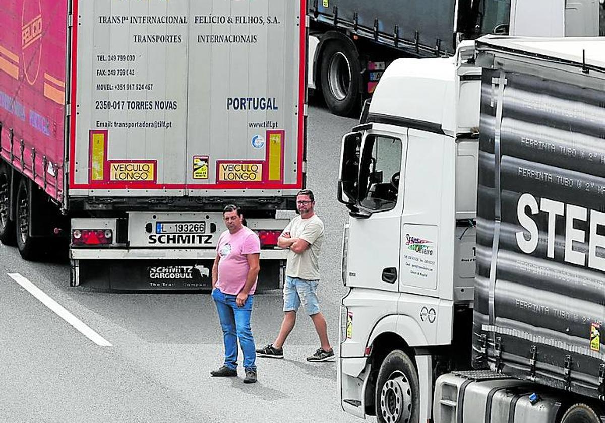 Dos transportistas atascados esperan en la calzada.